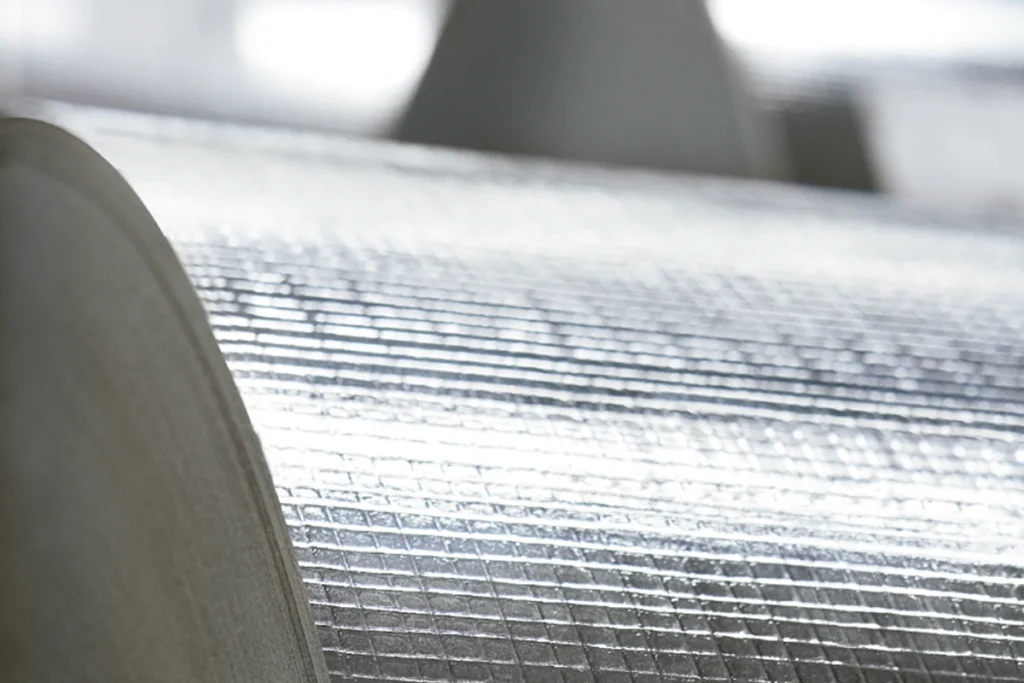 Recubrimiento por extrusión para materiales de aislamiento térmico y acústico utilizados en construcción, climatización y sistemas HVAC.